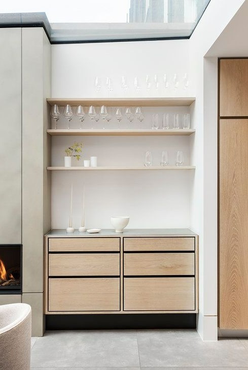 A small built in home bar with open shelves, sleek drawers and candles is a chic addition to your living room