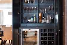 a sophisticated and beautiful built-in home bar of dark-stained wood, with a wine cooler, open storage compartments and glass shelves