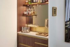 a stylish built-in bar with open shelves, a mirror, sleek drawers and lights is a cool and chic idea