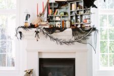 a unique Halloween mantel with black cheesecloth, blackbirds and owls, orange candles, books, skulls and lanterns is amazing