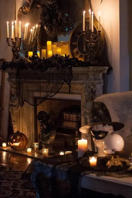 A vintage Halloween fireplace with black spiderweb and pillar candles, vintage candelabras, jack o lanterns and black faux blooms