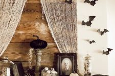 a vintage Halloween mantel styled with hay, spiders, pumpkins, skulls, black bats and blackbirds is a great idea