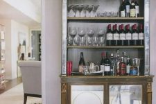 a vintage bookcase transformed into a chic home bar with glasses, bottles and everything else necessary in the cabinet part