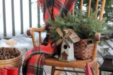 a vintage rocker, a plaid blanket, a basket with fir branches, a mini mill, a red star and boots for a rustic feel outdoors