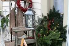 a vintage sleigh, a woodne star and a ladder, a candle lantern, a bucket with fir branches and lights and red ornaments in a box