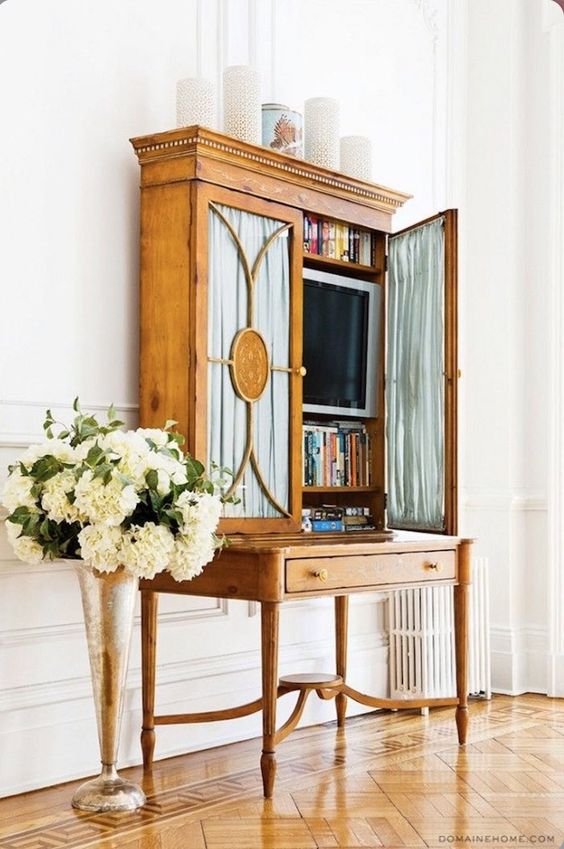 a vintage storage unit with a TV and books inside is a cool and chic idea for any room, it looks chic and beautiful