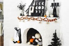 a white fireplace with colorful garlands with skulls, signs, black candles on a stand, black cheesecloth and branches and some pumpkins in the fireplace