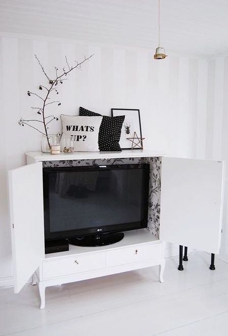 a white storage unit hiding a TV is a cool and smart idea for a Scandinavian living room, and you can make it yourself
