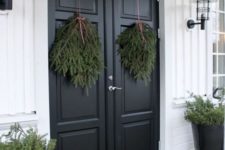 all-natural Christmas front door decor with evergreen posies, some evergreens on the floor and in pots