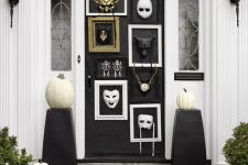 catchy front door Halloween styling with frames with masks, black stands with white pumpkins is a very cool and fresh idea