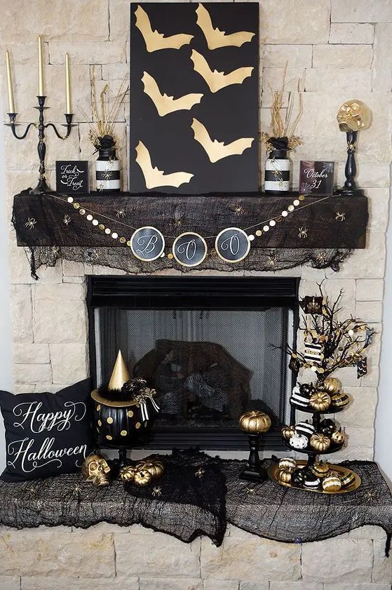 Glam black and gold Halloween decor   an artwork with gold bats, a gold garland, gold candles, pumpkins and black mesh