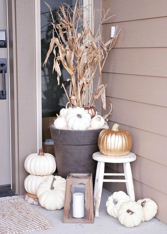 lots of white pumpkins, a wooden candle lantern and a corn husk arrangement to accent the porch and the door