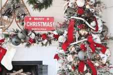 lovely grey, red and white Christmas decor with a tree with oversized bells, ribbons and lights, a matching garland on the mantel and vintage skis