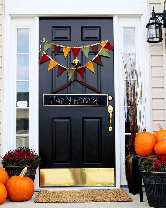 orange pumpkins, bold fall blooms in pots, a colorful bunting and a chalkboard sign for simple Thanksgiving decor