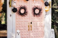 pretty Halloween front doors with black branch and snake wreaths, pastel and black pumpkins over them and mini ghosts on the floor