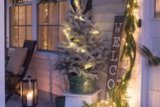 rustic Christmas decor with a fir garland with lights, a vine ball with lights and fir, a flocked Christmas tree with lights and wreaths