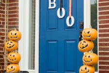 stacked jack-o-lanterns and letters hanging on the door instead of a usual Halloween wreath are a great idea to go for