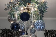 a beautiful Christmas chandelier of navy, light blue and silver ornaments, frozen branches, twigs and candles is wow