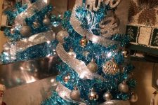 a blue Christmas tree with silver and glitter ornaments, glitter ribbons and a bow on top plus letters is amazing as an additional one