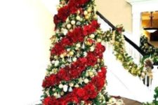 a bold Christmas tree with gold ornaments and a fluffy red garland plus a large red bow on top