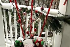 a bold outdoor Christmas decoration of a vase iwth fir branches, bright ornaments and large candy canes is whimsical and bright