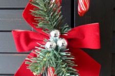 a candy cane with a red bow, fir twigs and bells is a lovely Christmas decoration or ornament