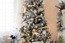 a chic Christmas tree with lights, white, black and gold glitter ornaments and striped ribbons is a very bright and cool idea