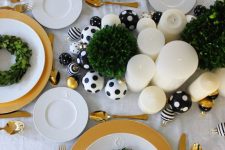 a chic and glam Christmas tablescape with black and white polka dot ornaments, pillar candles and greenery wreaths plus gold cutlery and chargers
