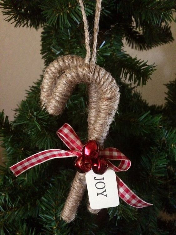 A cozy rustic Christmas ornament   a twine wrapped candy cane with red bells and a plaid bow is a lovely idea