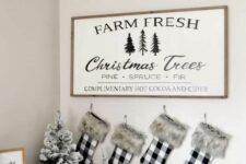 a farmhouse Christmas sign with a stained frame and black printing is a cool and chic idea for any farmhouse home