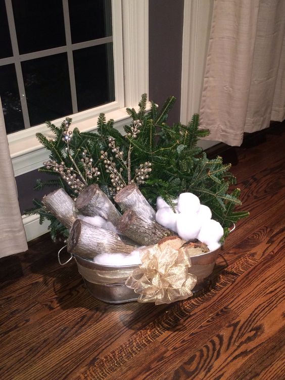 a galvanized bathtub with firewood, snowballs, fir branches, berries and a bow is a cool outdoor decoration for Christmas
