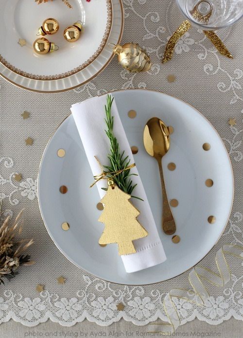 a gold and white Christmas tablescape with a lace runner, gold stars and polka dots, gold cutlery and ornaments