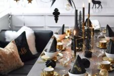 a gorgeous silver, gold and black NYE tablescape with gold chargers, cutlery, mugs, candleholders and black candles plus an oversized black paper star