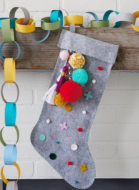 A grey felt stocking with colorful detailing   polka dots, crosses and pompoms and tassels is a lovely DIY piece for a modern space