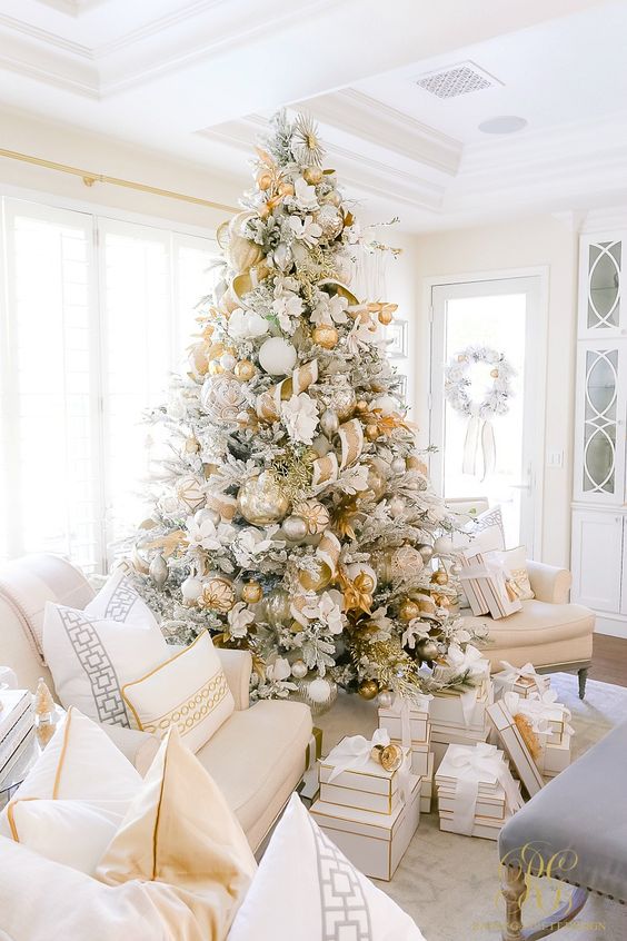 A jaw dropping Christmas tree with oversized gold, silver and white ornaments, gold and white ribbons and white fabric blooms