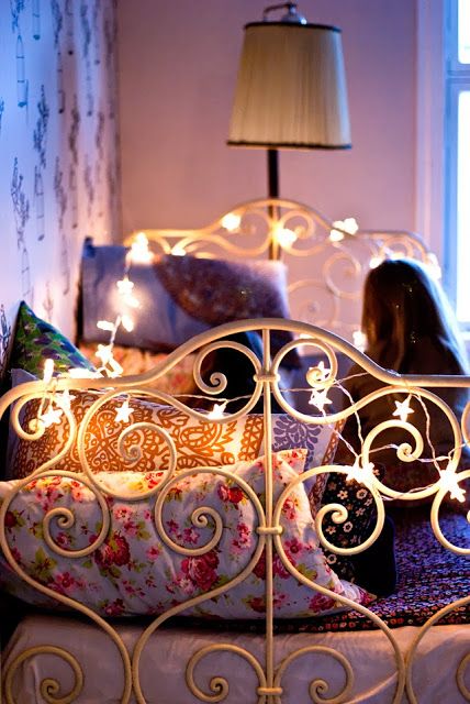 a metal bed accented with star-shaped string lights covering the headboard and foot of the bed, printed bedding