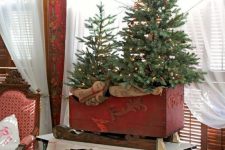 a red box sleigh with Christmas trees with lights and burlap is amazing for rustic holiday decor with a vintage feel