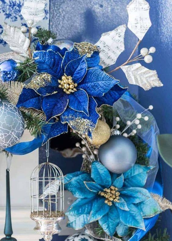 a refined Christmas wreath with silver, gold ornaments and bold blue and light blue blooms and a silver cage with a bird
