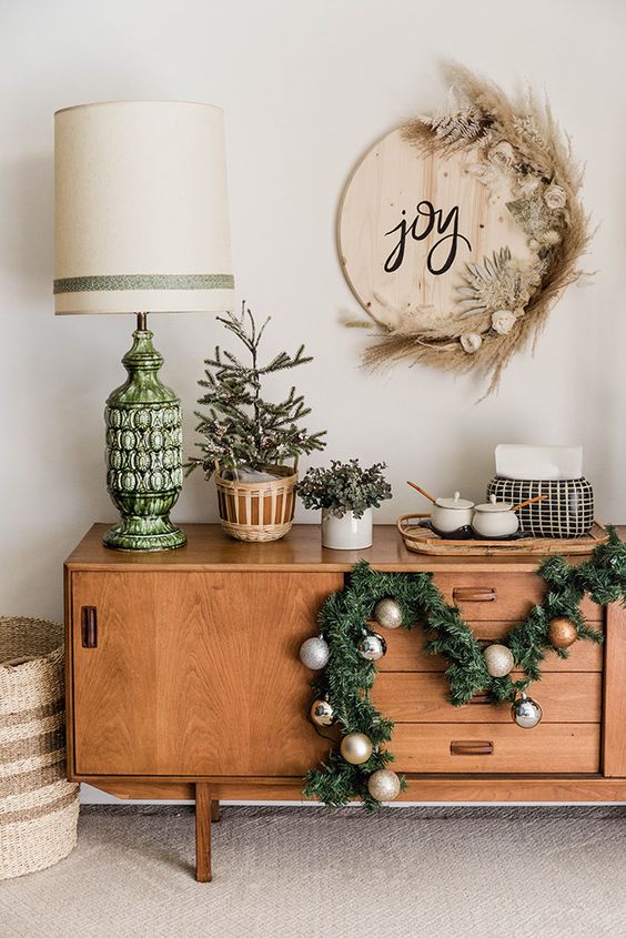 a round boho Christmas wooden sign with JOY letters, white blooms, pampas grass and dried leaves is amazing
