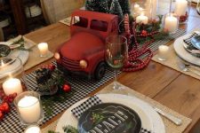 a rustic retro Christmas tablescape with a buffalo check runner and napkins, woven placemats, a red truck with bottle brush Christmas trees and candles