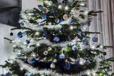 a shining Christmas tree with lights, blue, navy and silver ornaments and stars is a beautiful and chic idea