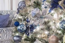 a silver Christmas tree with silver, light blue and navy ornaments, fabric blooms and ribbons is a very chic and glam idea