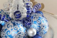 a simple Christmas centerpiece of a silver plate, silver, silver glitter and blue ornaments is a stylish and bright decoration