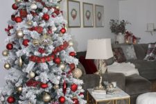 a snowy Christmas tree with gold and red ornaments, plaid ribbons and a silver tree topper