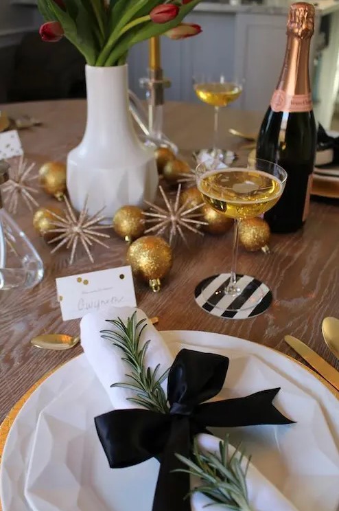 a sparkly tablescape with glitter ornaments, tulips, evergreens and black and white touches