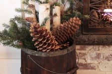 a stained wooden bucket with oversized pinecones, firewood, evergreens is a pretty rustic Christmas decoration to rock
