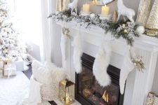 a super refined gold and white Christmas mantel with gilded Christmas mini trees and candleholders, white deer, large metlalic trees and white stockings with gold leaves