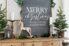 an awesome chalkboard Christmas sign decorated with greeneyr on top is a stylish farmhouse holiday decor idea
