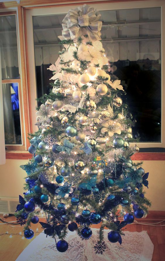 an ombre Christmas tree from white to light blue and navy and with a large white and silver bow on top is amazing