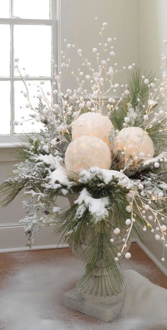 an outdoor Christmas arrangement of oversized snowballs, fir branches, snowy branches and berries plus lights
